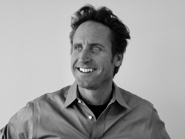 Black-and-white portrait of Jay Froberg, smiling and looking away from the camera